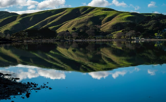 Calm mountain lake with green hills reflecting in the water