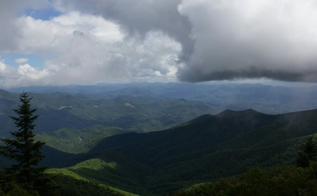 Fully forested Blue Ridge ridges under dark storm clouds building overhead, no bare rock or scree